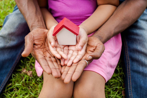 Hands of family together holding house in green park - family home and real estate concept - Foto, Imagem