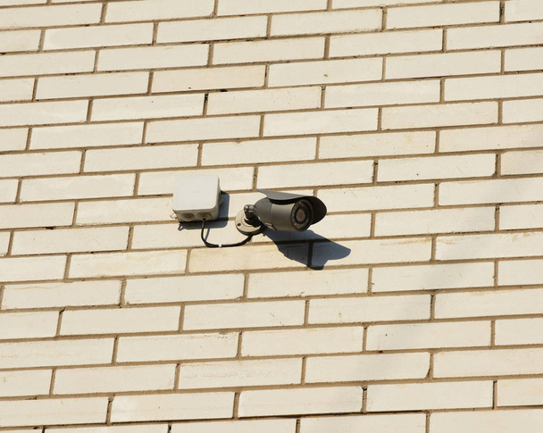 Security CCTV camera is mounted on a white brick house wall. - Photo, Image