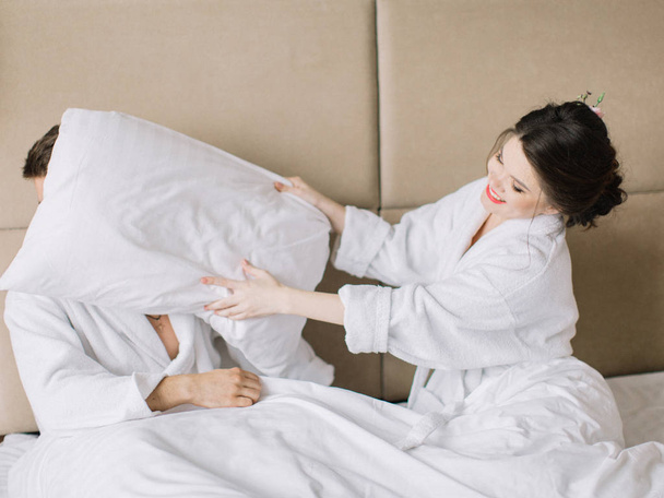 чоловік і жінка борються з подушками весело в ліжку
  - Фото, зображення