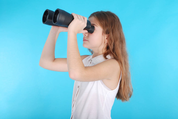 Young girl with binoculars looking up at copy space - Foto, Imagen