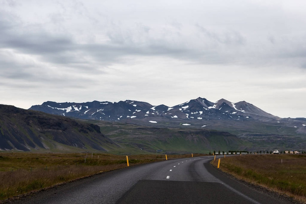 Iceland road with mountains covered with snow on the horizon Empty road in rural Icelandic - Фото, зображення