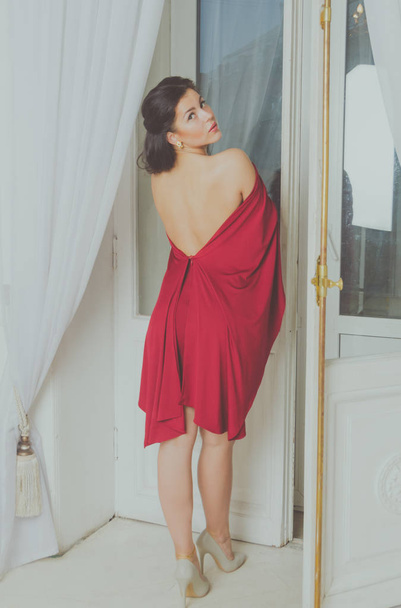  window-beautiful girl in a red dress. - Foto, Imagen