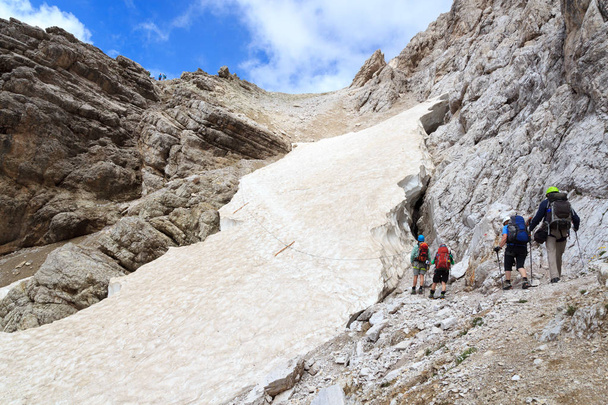 Люди, поднимающиеся на Виа Феррата Северино Казара и снежное поле в горах Секстен Доломиты, Южный Тироль, Италия
 - Фото, изображение