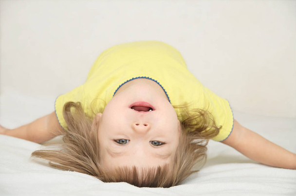happy funny little girl arched back lying on bed isolated, hap - Foto, Imagen