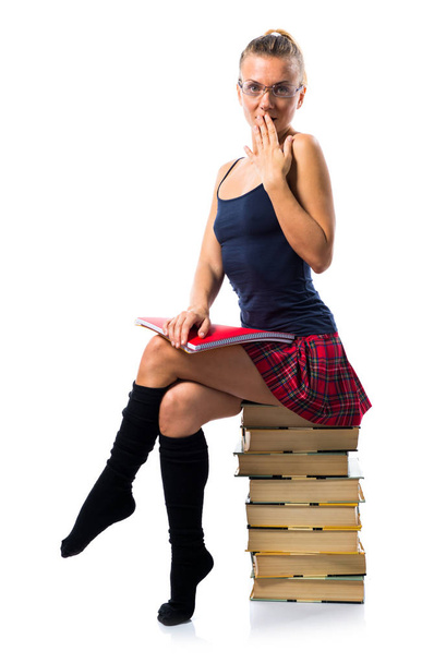 Jolie écolière blonde assise sur de nombreux livres et tenant coll
 - Photo, image