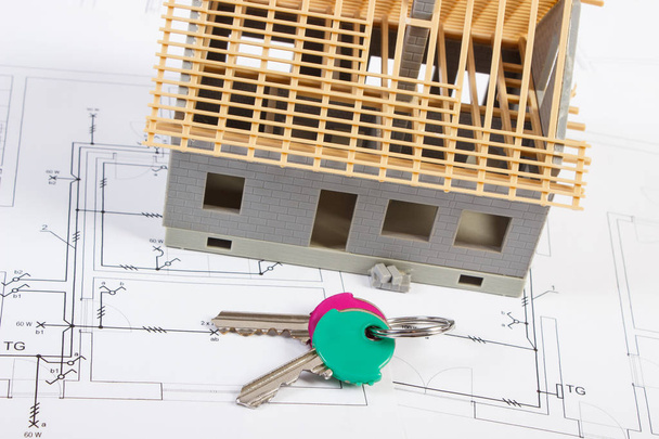 Домашні ключі та невеликий будинок, що будується на електричних кресленнях, концепція будівництва будинку
 - Фото, зображення