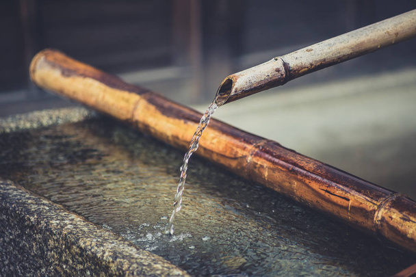 Rinçage à l'eau avec tuyau en bambou dans une baignoire en pierre au temple japonais
. - Photo, image