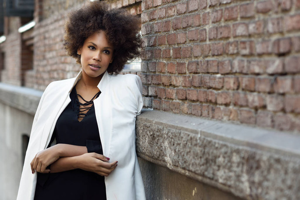 Młody czarny kobieta z fryzura afro stojący w miejskich backgrou - Zdjęcie, obraz