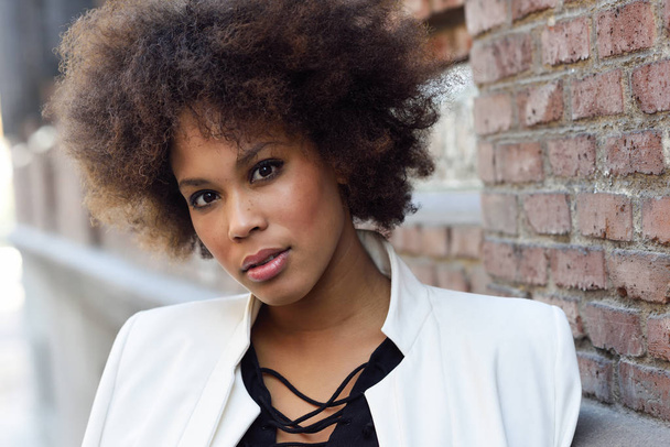 Joven mujer negra con peinado afro de pie en el fondo urbano
 - Foto, Imagen