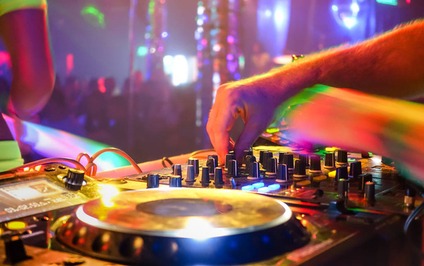 Close up of dj playing party music on modern cd usb player in disco club - Nightlife and entertainment concept  - Defocused background with shallow depth of field and focus on buttons near mixing hand - Foto, imagen