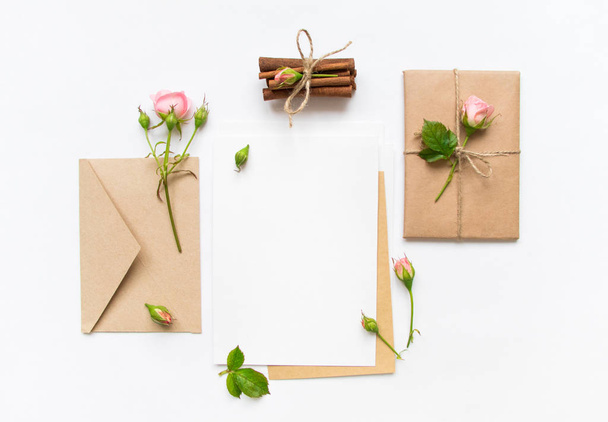 Letter, envelope and gift on white background. Invitation cards, or love letter with pink roses. Holiday concept, top view, flat lay - Fotografie, Obrázek