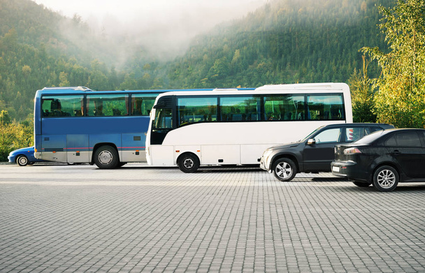 Cars and buses in a parking lot on mountains background - Photo, image