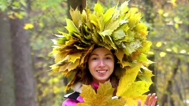Piękna dziewczyna gra chowanego w lesie z wieniec żółte liście na głowie. - Materiał filmowy, wideo