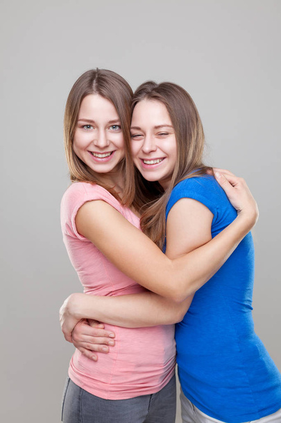 Студийный портэйт молодых сестер-близнецов, обнимающих
 - Фото, изображение