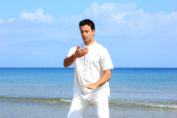 Handsome man on the beach meditating - Foto, Bild