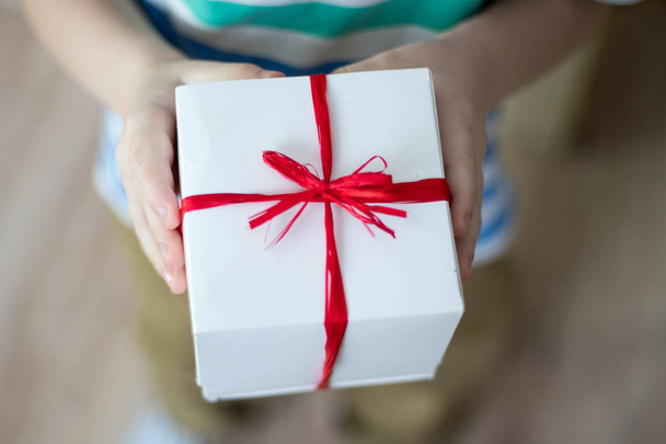 Schachtel mit einem Geschenk in den Händen eines Kindes - Foto, Bild