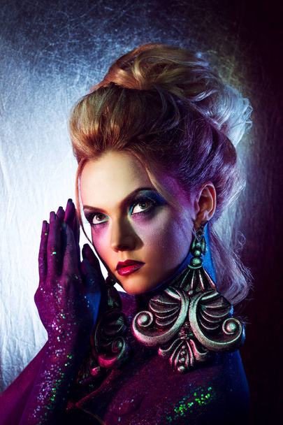 Young attractive blonde girl in bright art-makeup, high hair, body painting. Rhinestones and glitter - Foto, Imagen