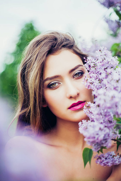 Portrait of young beautiful woman posing among lilac trees. - 写真・画像