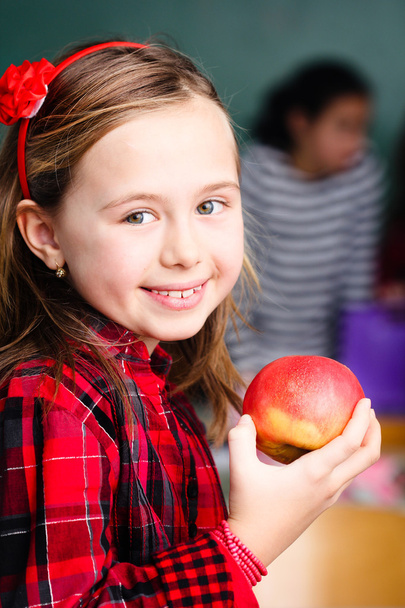 gelukkig weinig schoolmeisje met apple - portret in klas - Foto, afbeelding