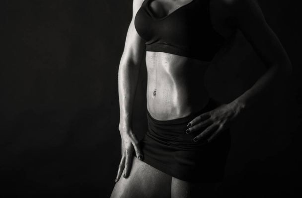 Elegant training, muscular woman on a black background - Photo, Image