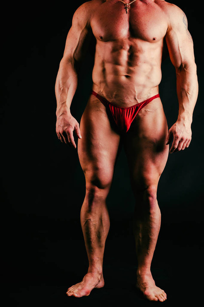 Um homem com um corpo muscular lindo em um fundo preto
 - Foto, Imagem