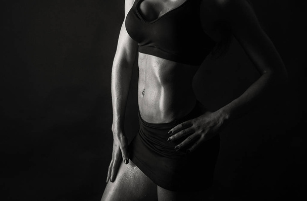 Elegant training, muscular woman on a black background - Photo, Image