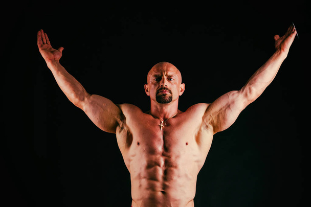 Un hombre con un cuerpo musculoso magnífico sobre un fondo negro
 - Foto, Imagen