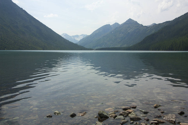 Lake in the mountains between the mountain peaks. - Φωτογραφία, εικόνα