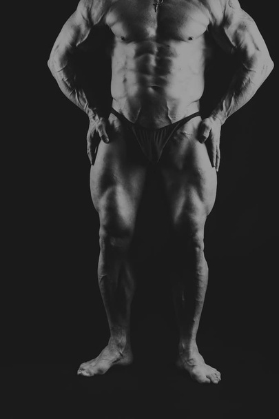 Un hombre con un cuerpo musculoso magnífico sobre un fondo negro
 - Foto, imagen