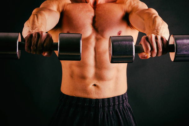 Forte fisiculturista com seis pack, abdominais perfeitos, ombros, bíceps
 - Foto, Imagem