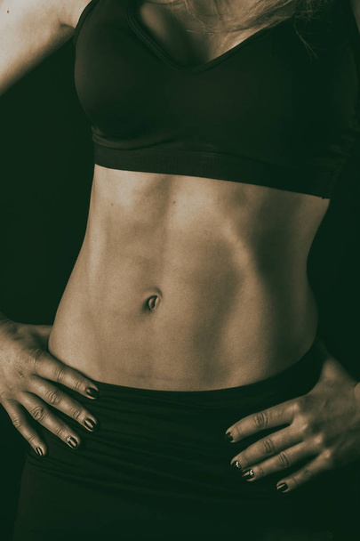 Fitness lichaam van de vrouw op een zwarte achtergrond - Foto, afbeelding