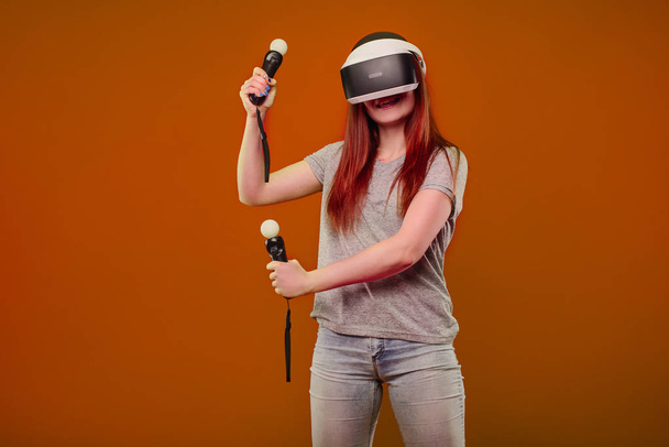 Joyeuse jeune fille utilisant un casque VR et souriant isolé sur fond orange
 - Photo, image