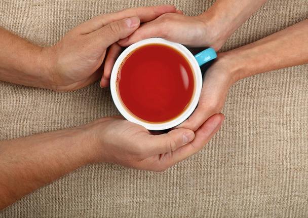 Man and woman hands holding full black tea cup - Foto, imagen