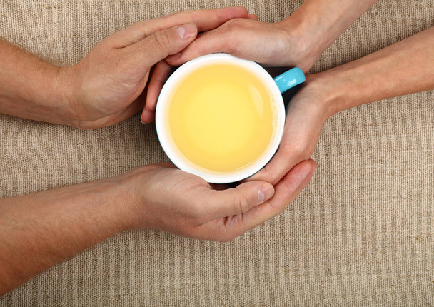 Man and woman hands hold full green tea cup - Photo, Image