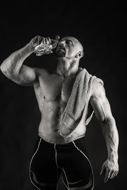Novice bodybuilder posing on a black background - Photo, Image