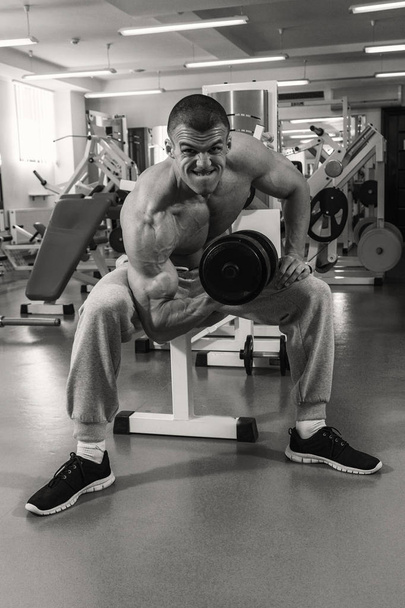 Hombre con una mancuerna en el gimnasio
 - Foto, Imagen