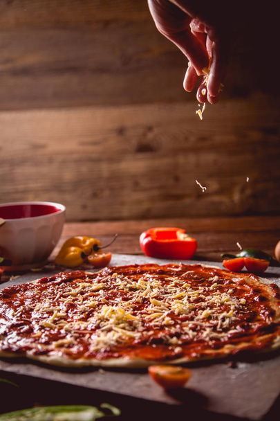 Girl is spreading cheese on tasty homemade pizza  - 写真・画像
