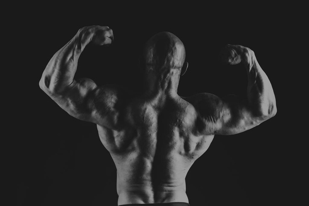 bodybuilder op een zwarte achtergrond - Foto, afbeelding
