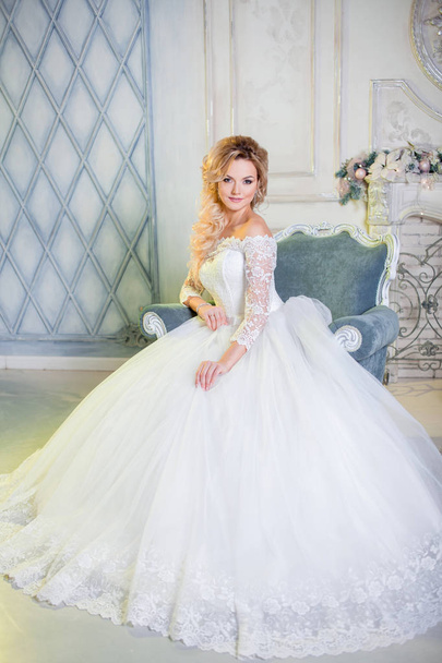 Portrait of charming woman in wedding dress. The girl bride sits in a chair - Фото, изображение