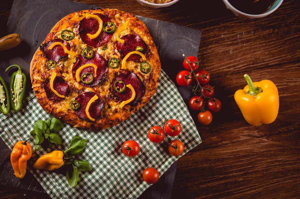 Fresh and tasty homemade pizza on wooden table with ingredients - Foto, Bild