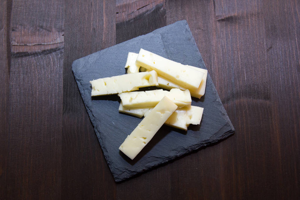 Pieces of cheese on slate plate on wood from above - Zdjęcie, obraz