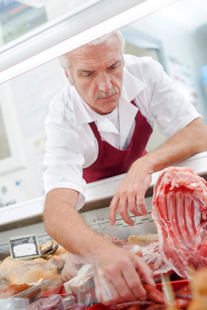 Butcher getting sausages from counter - Photo, image