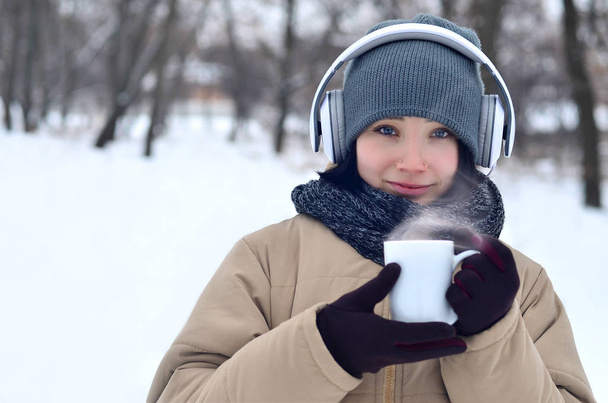 Chica joven con auriculares y taza de café
 - Foto, Imagen