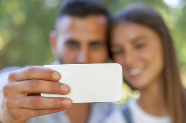 lovely couple of young adults take a selfie in the park - Fotografie, Obrázek