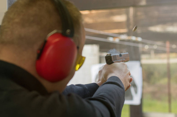 Shooting with a pistol. Man Firing pistol in shooting range.  - Foto, Bild