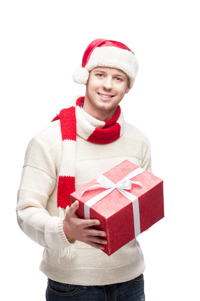 Young man in santa hat holding big red christmas gift - Fotoğraf, Görsel