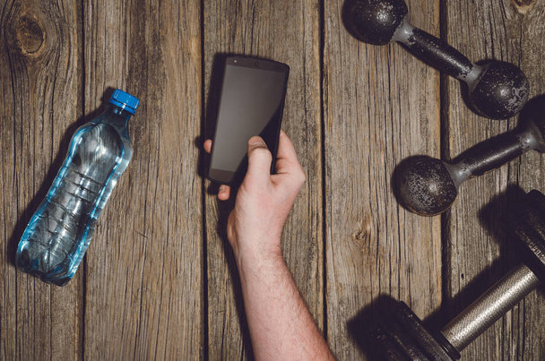 Fitness workout background. Hand holding a smartphone - Foto, Imagem