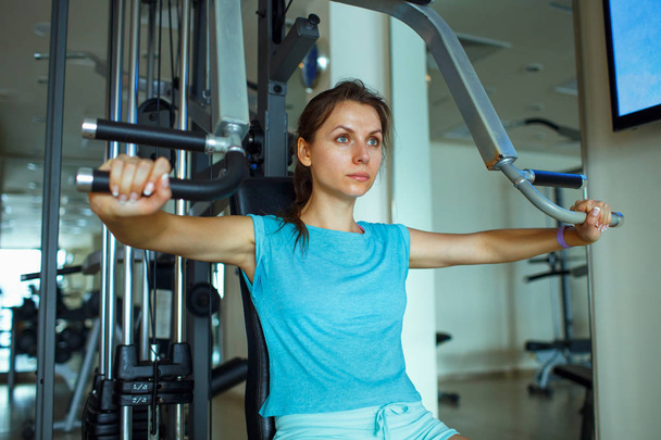 Femme travaille sur les appareils d'entraînement dans le centre de fitness
 - Photo, image