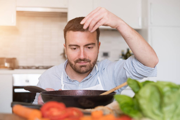 Homem cozinhar em casa e preparar comida
 - Foto, Imagem