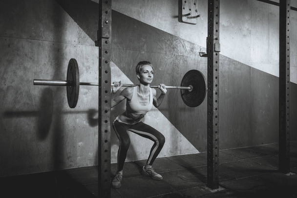Gym. She squats with a barbell - Photo, Image